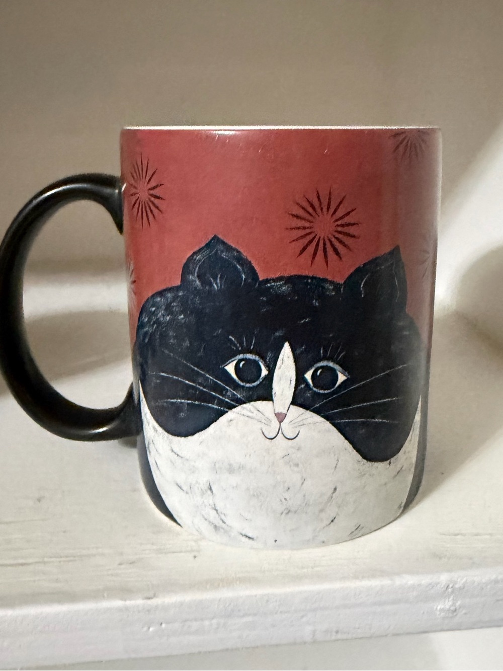 A vintage ceramic coffee mug featuring Warren Kimble's "Jellicle Cat" artwork.